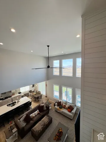 Two-story living area with recessed lighting, large windows, and a ceiling fan