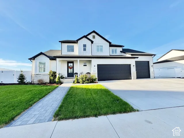 Modern two-story residence with white siding, black trim, a covered porch, an attached two-car garage, and a paver walkway