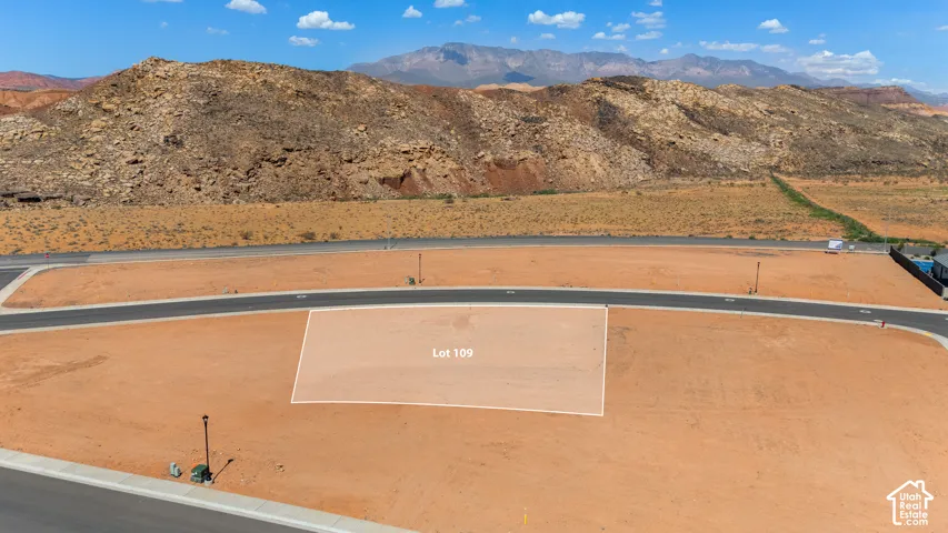 Expansive desert lot featuring a paved roadway and distant mountain backdrop