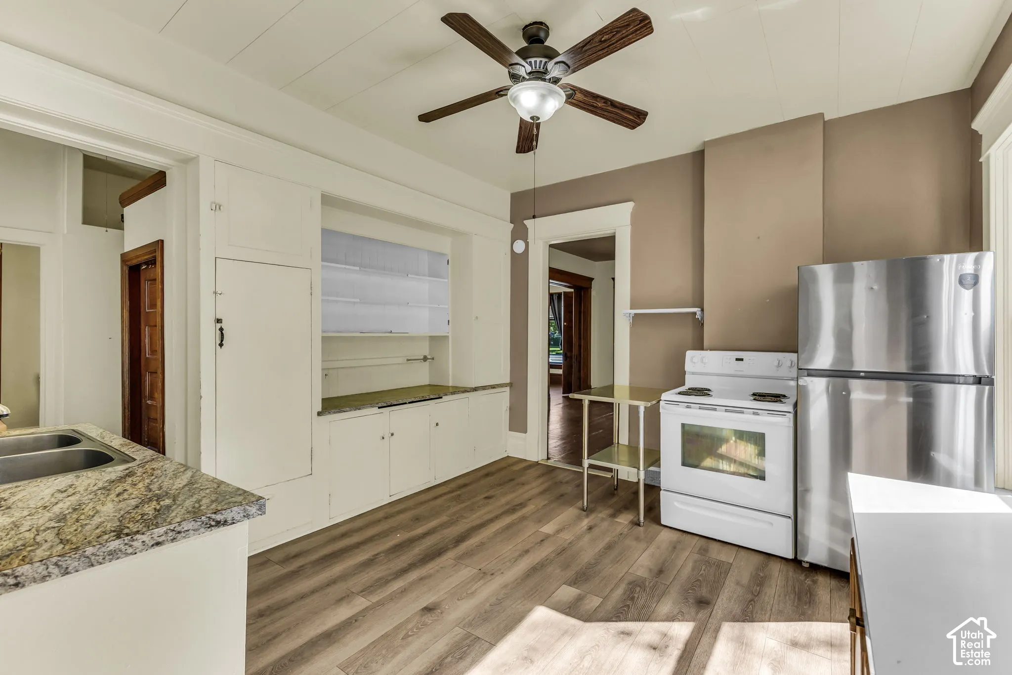 Wood-finish flooring, built-in cabinetry, ceiling fan with light fixture, and a stone-finish countertop