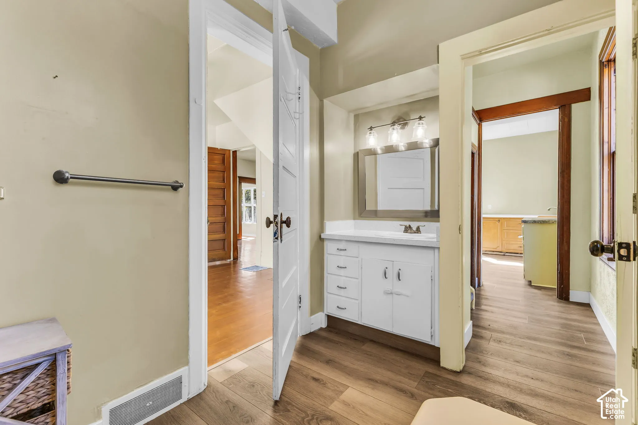 White vanity with integrated sink, rectangular mirror, and a three-light fixture