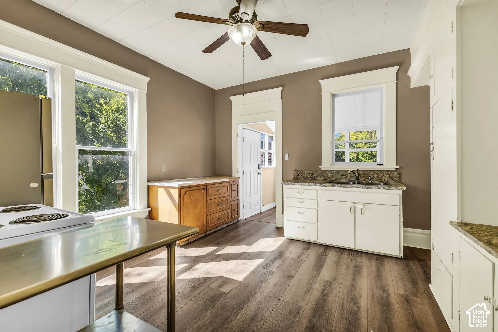 Wood-finish flooring, white cabinetry, integrated sink, granite-style countertops, and a ceiling fan
