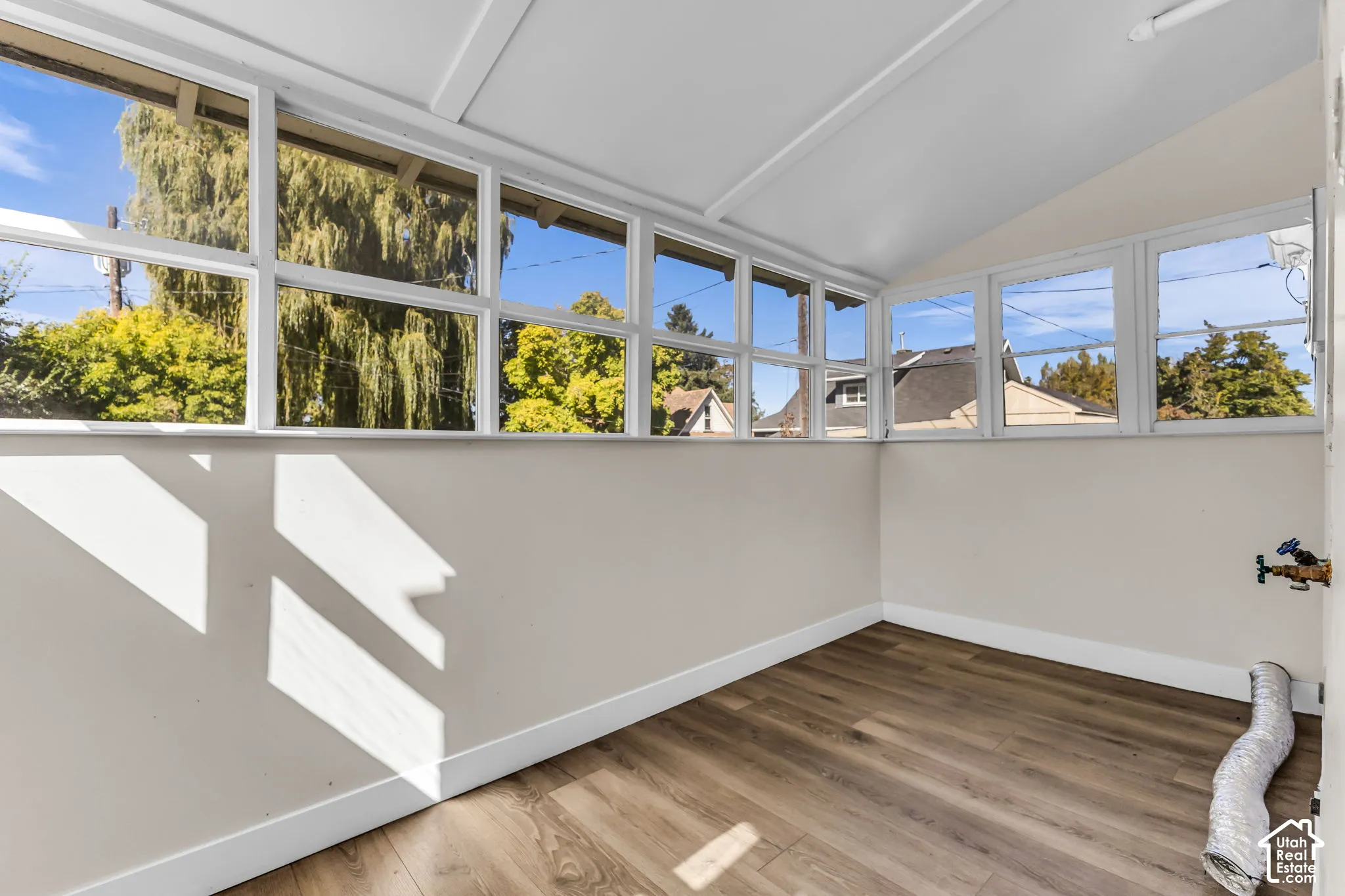 Wood-finish flooring with white baseboards, surrounded by multiple windows