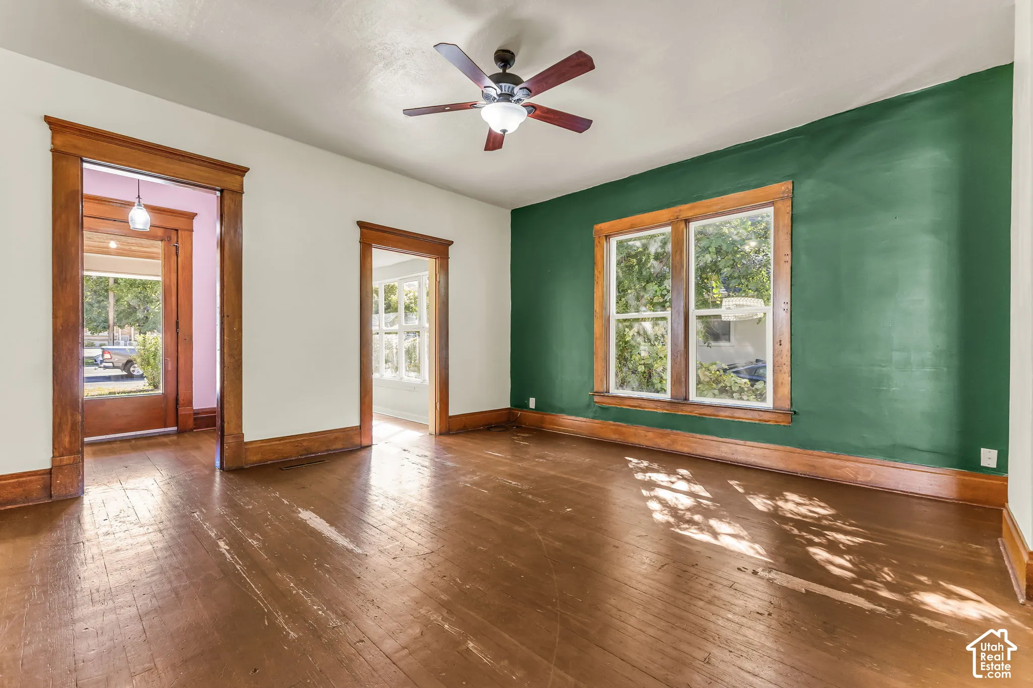 Wood-finish flooring, wood trim, and a ceiling fan with integrated lighting