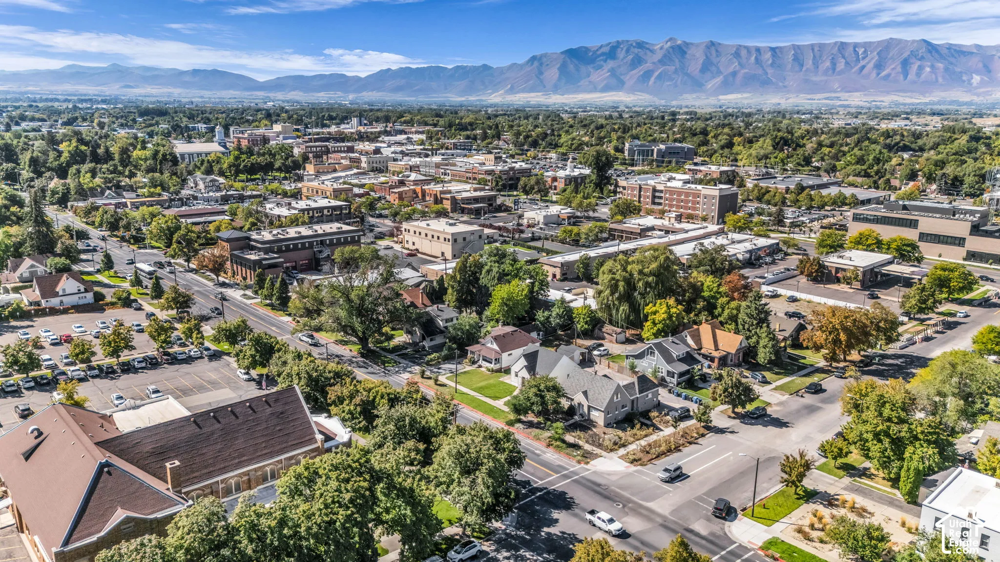 Dense urban area with varied architectural styles, established landscaping, and mountain backdrop