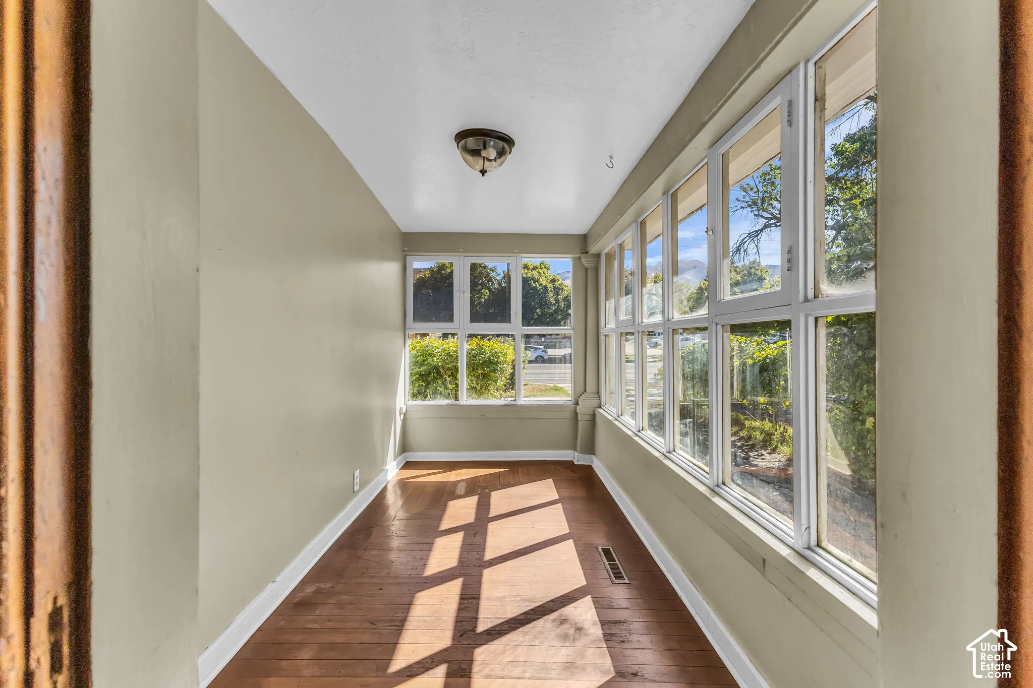 Hardwood flooring with natural light, neutral wall tones, and multiple fixed windows