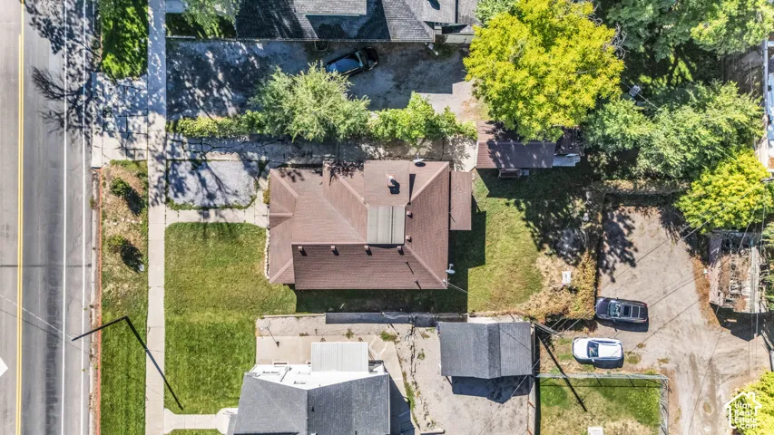 Pitched roof structure with mature trees, a well-maintained lawn, and a sidewalk