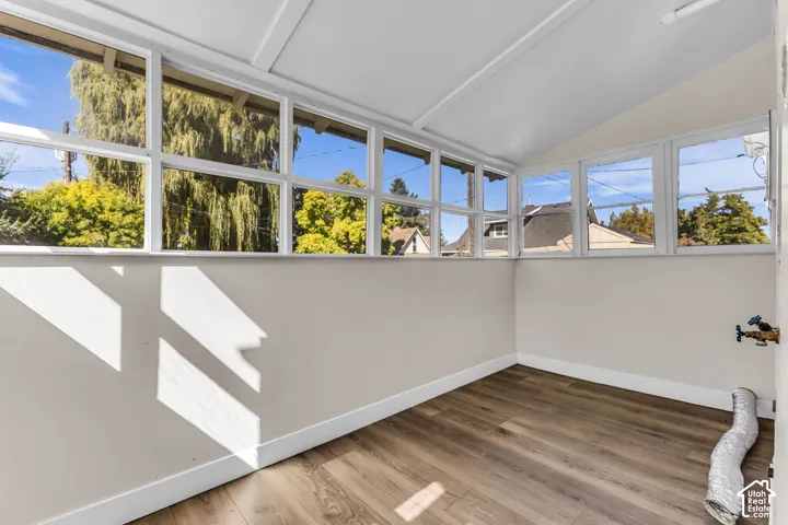 Wood-finish flooring with white baseboards, surrounded by multiple windows