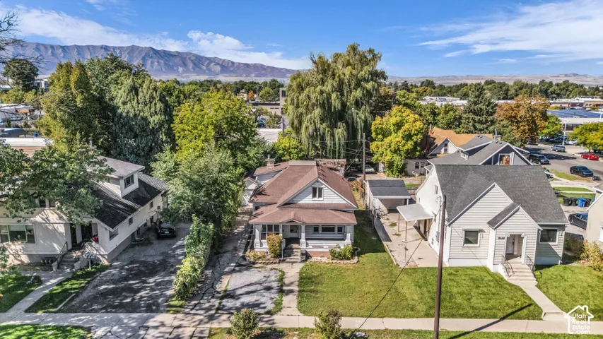 Mountain backdrop with clear skies, lush green trees, and multiple residential structures