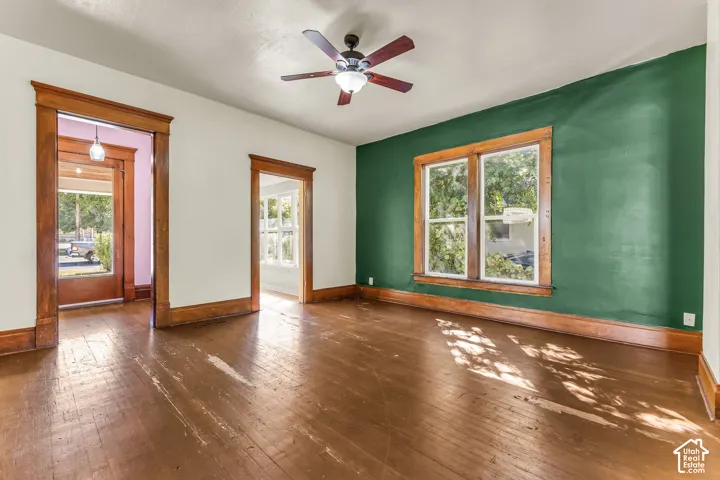 Wood-finish flooring, wood trim, and a ceiling fan with integrated lighting