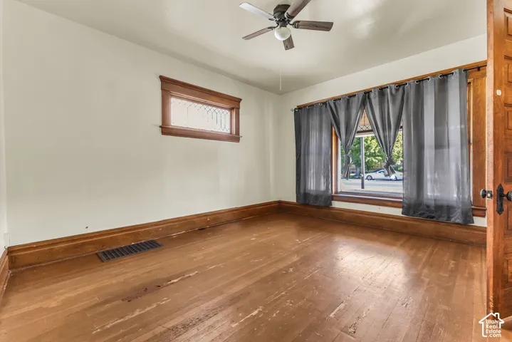 Hardwood flooring, wood trim, ceiling fan, transom window, and a paneled wood door