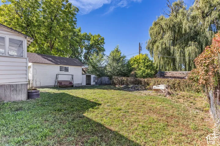 Expansive backyard with a separate garage structure, additional storage shed, and mature perimeter trees