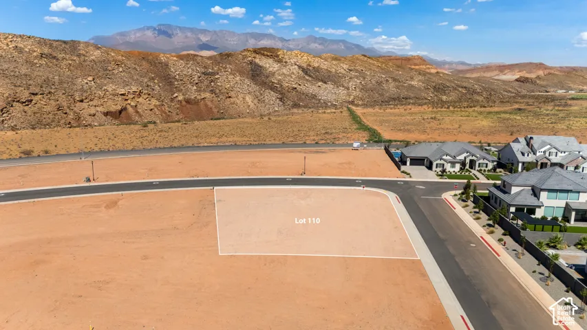 Expansive undeveloped lot featuring street frontage, adjacent to paved roadways, and surrounded by natural terrain