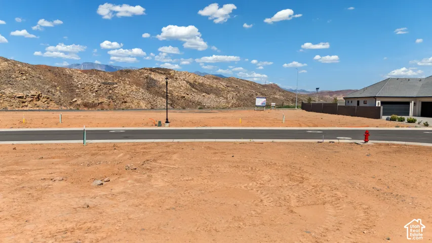 Expansive land parcel featuring established paved road access, visible utilities, and a mountain backdrop