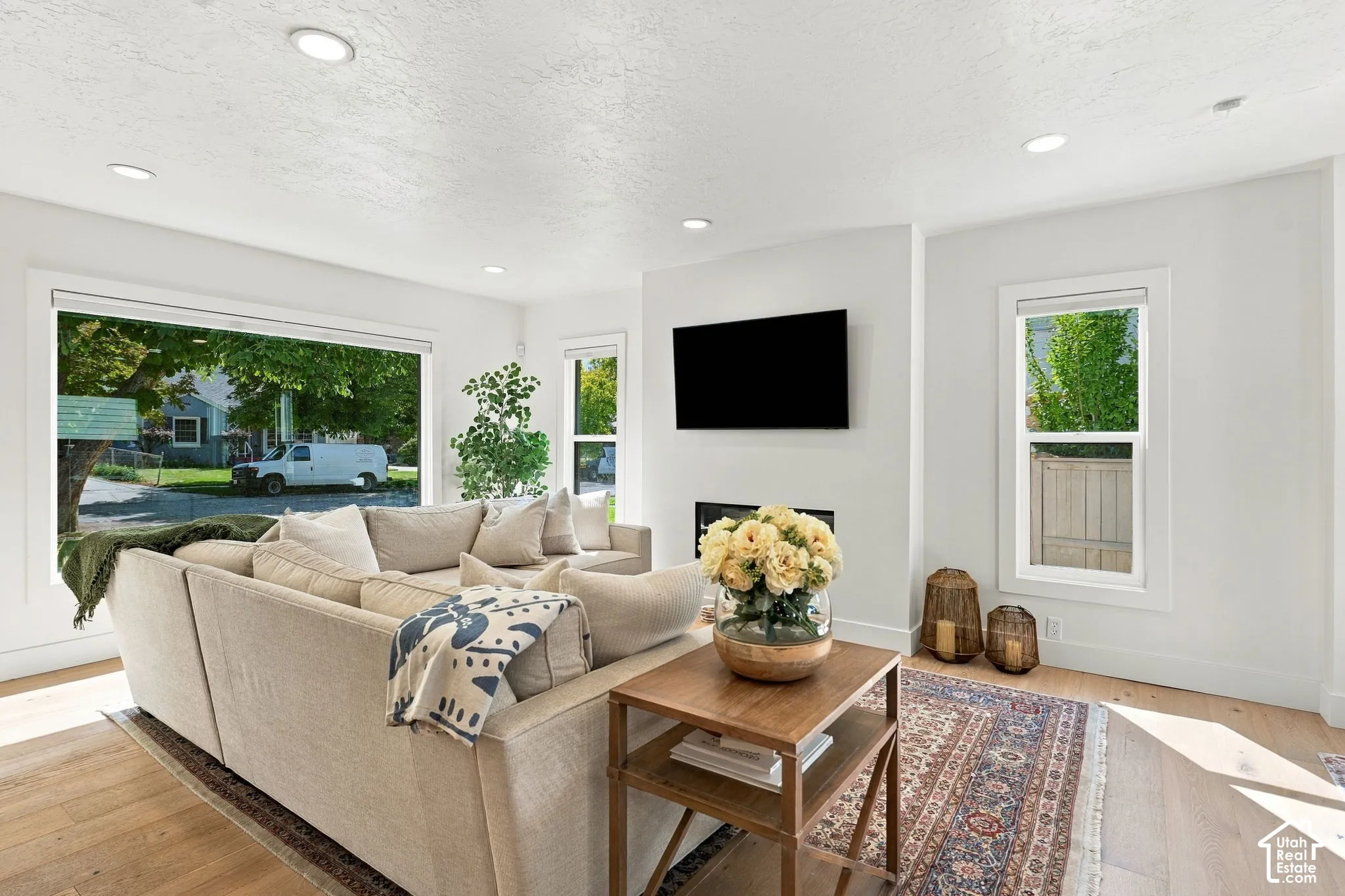 Recessed ceiling lighting, wood-finish flooring, white walls, and a built-in fireplace