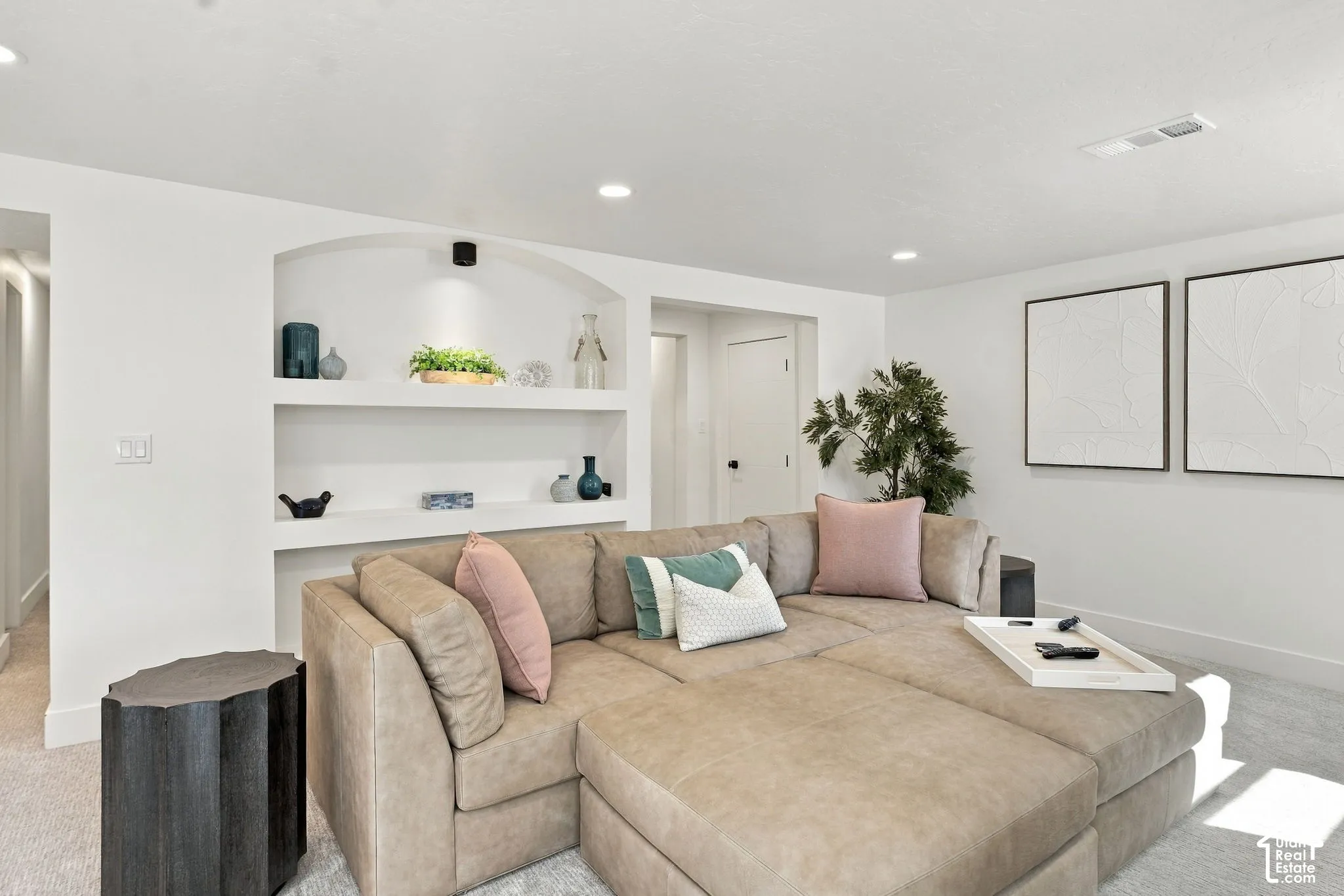 Built-in arched shelving with integrated lighting, recessed ceiling lights, and light-toned carpeting