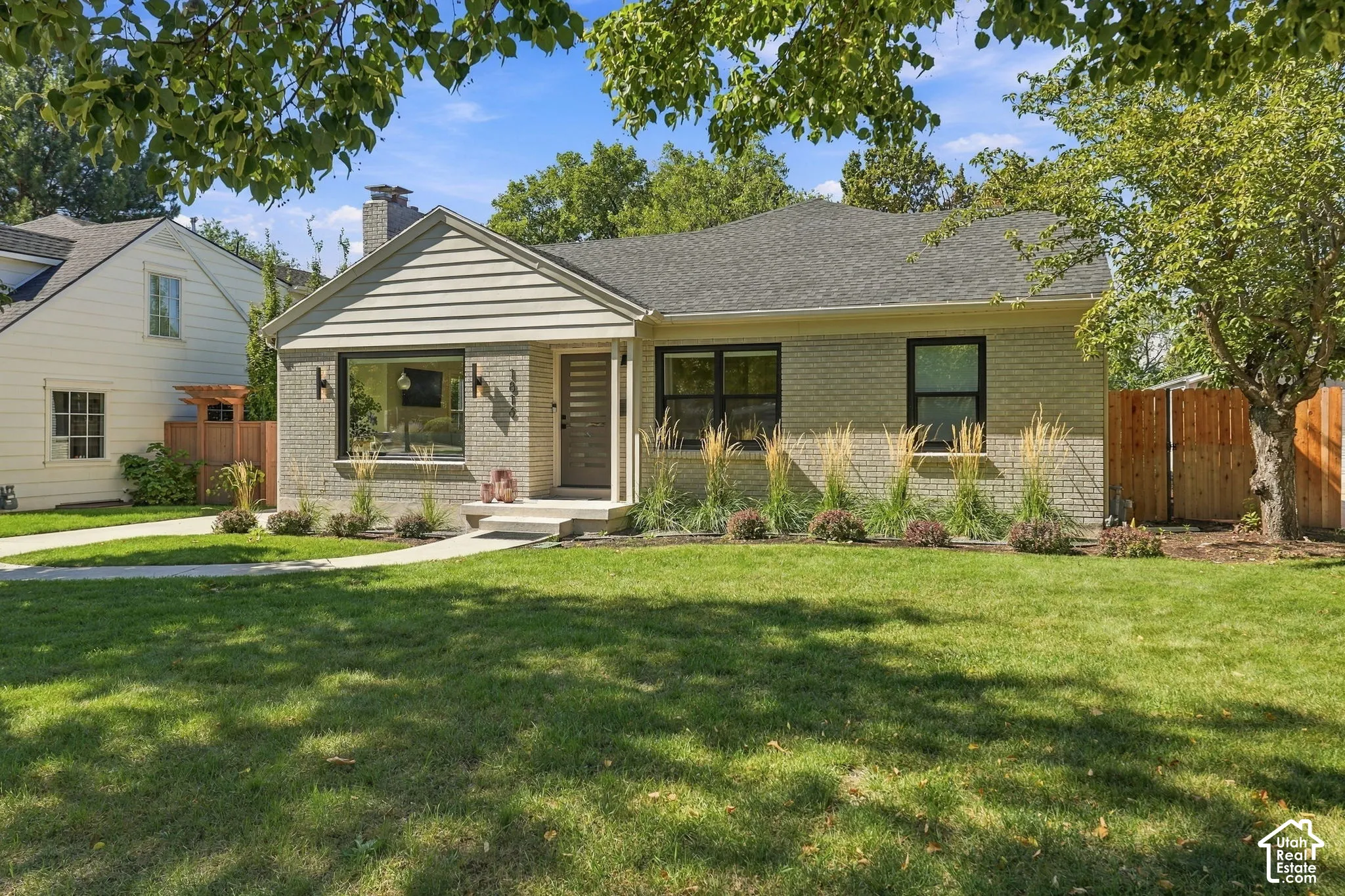 Light-colored brick exterior with a contrasting dark roof, featuring a prominent front gable with horizontal siding
