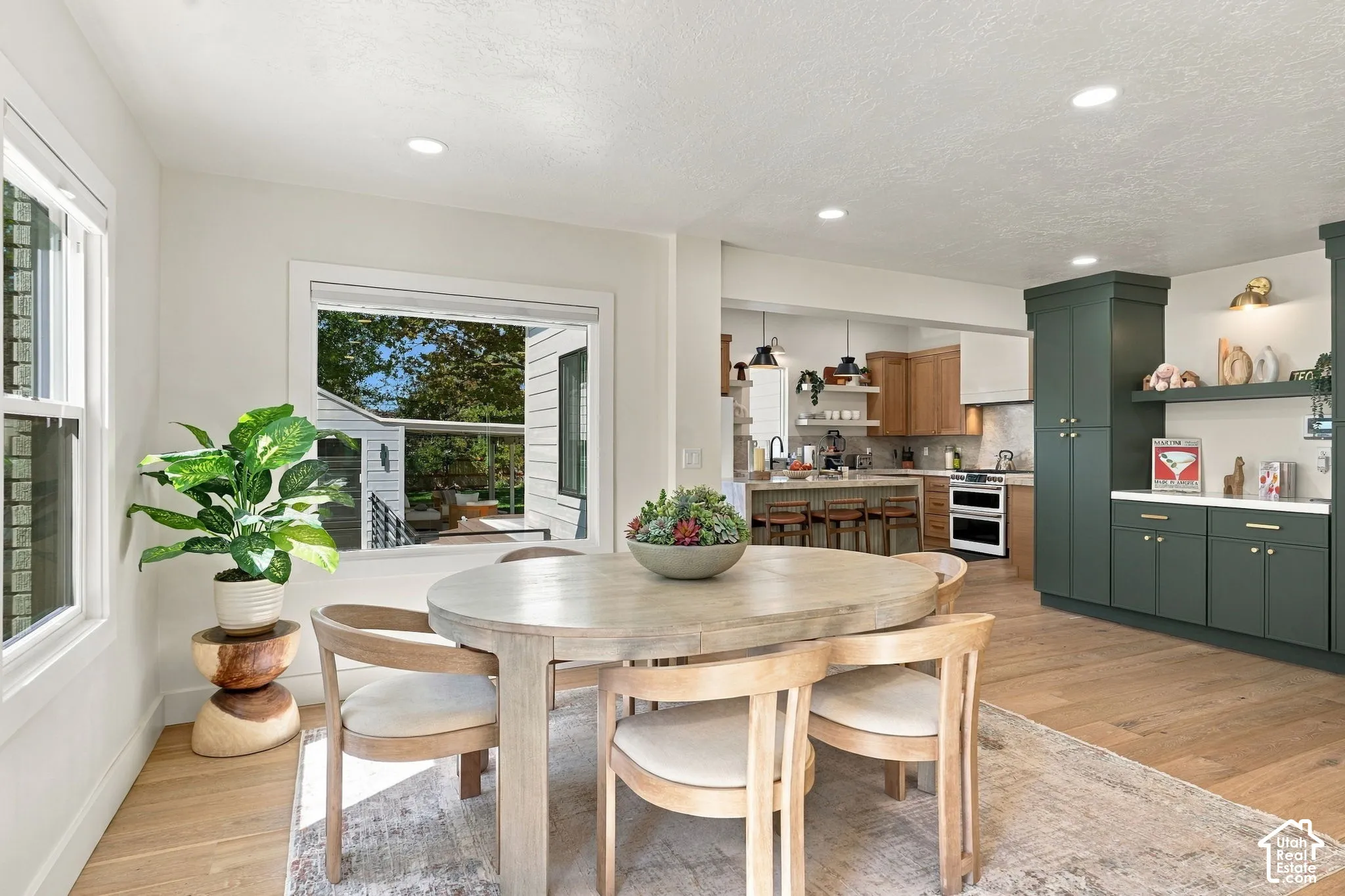 Recessed lighting illuminates the dining area with light wood-finish flooring