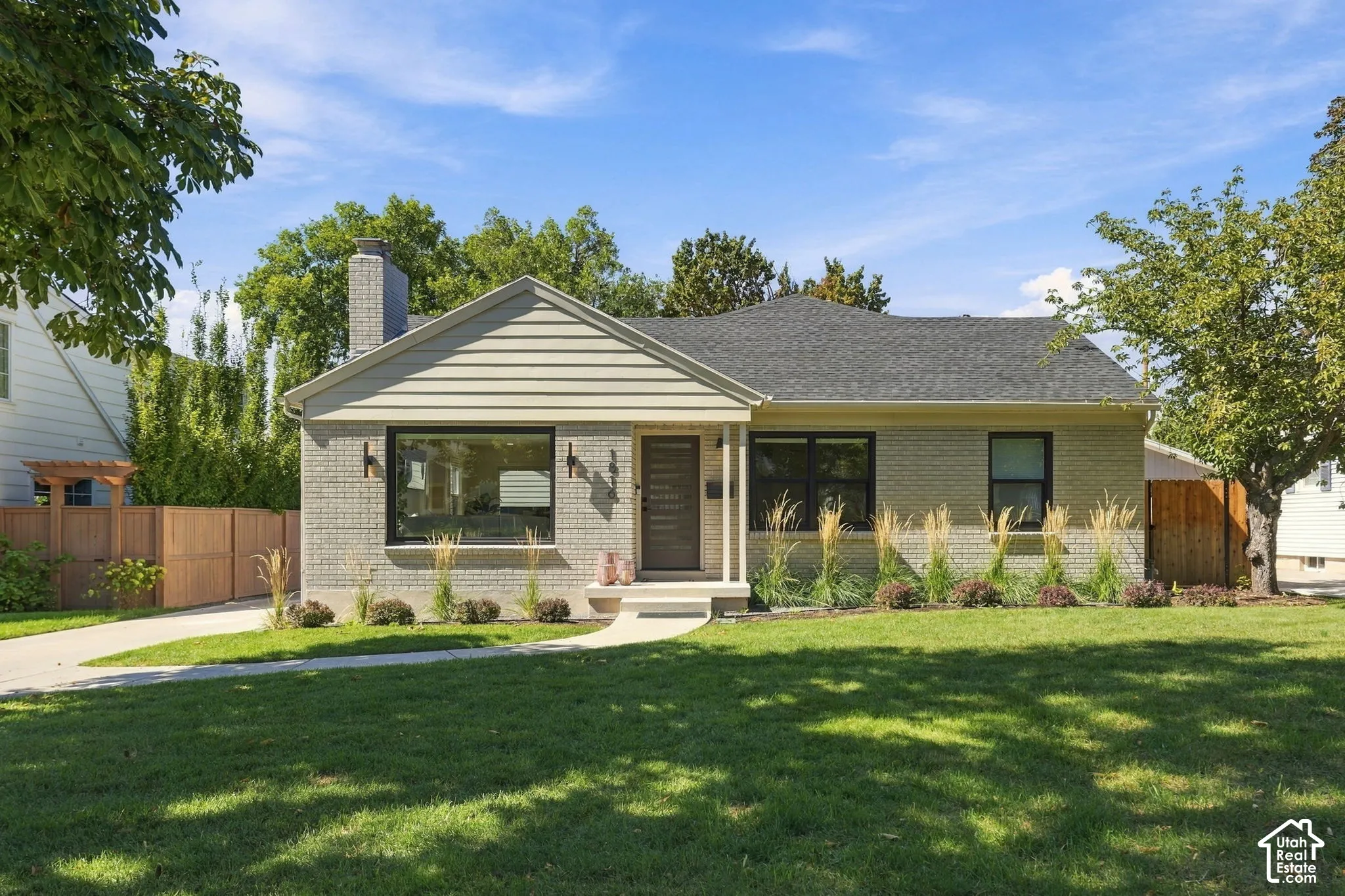 Gray brick exterior with a contrasting gable, dark-framed windows, and a prominent chimney