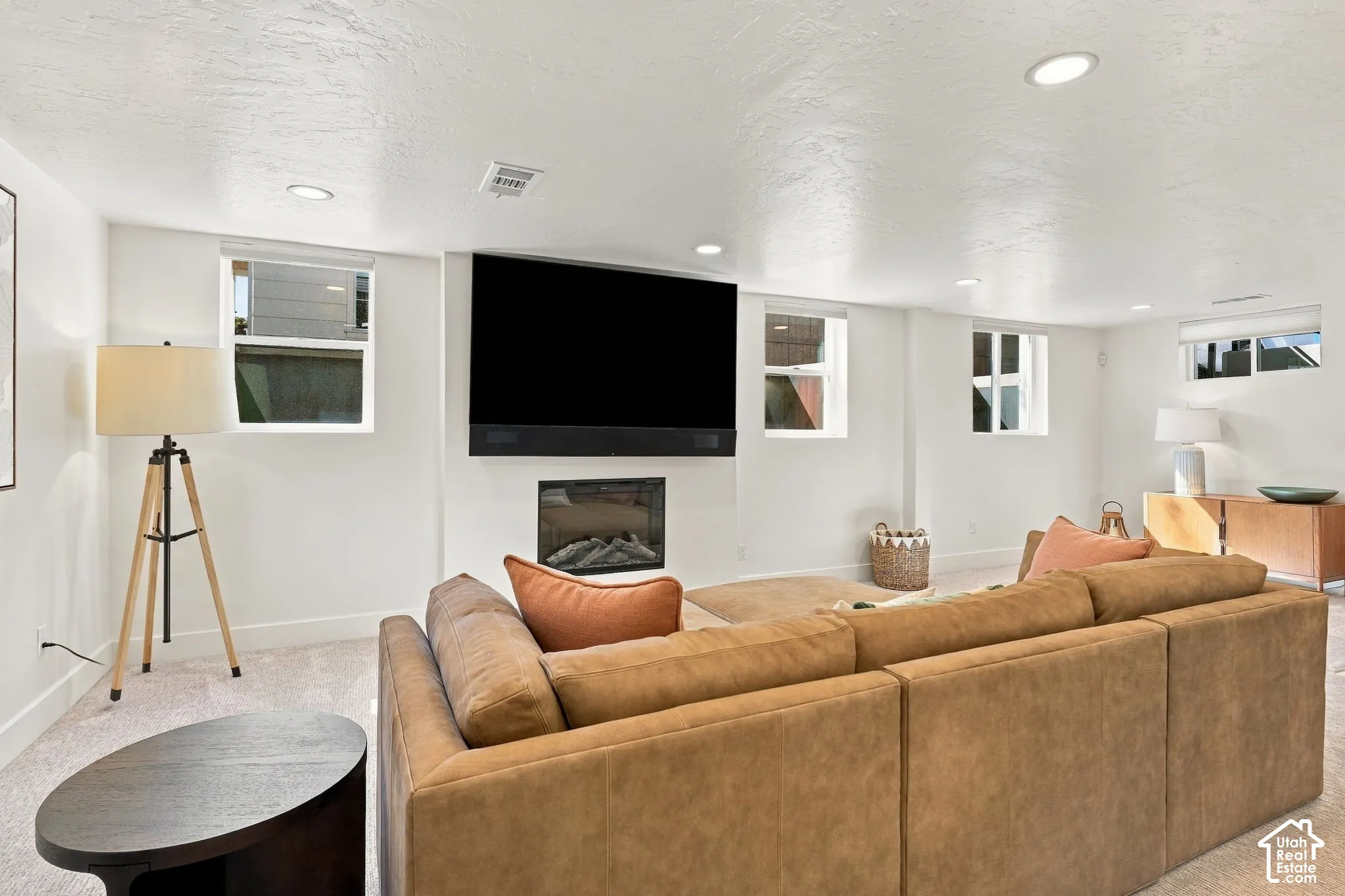 Recessed lighting illuminates the carpeted floor, complemented by multiple windows