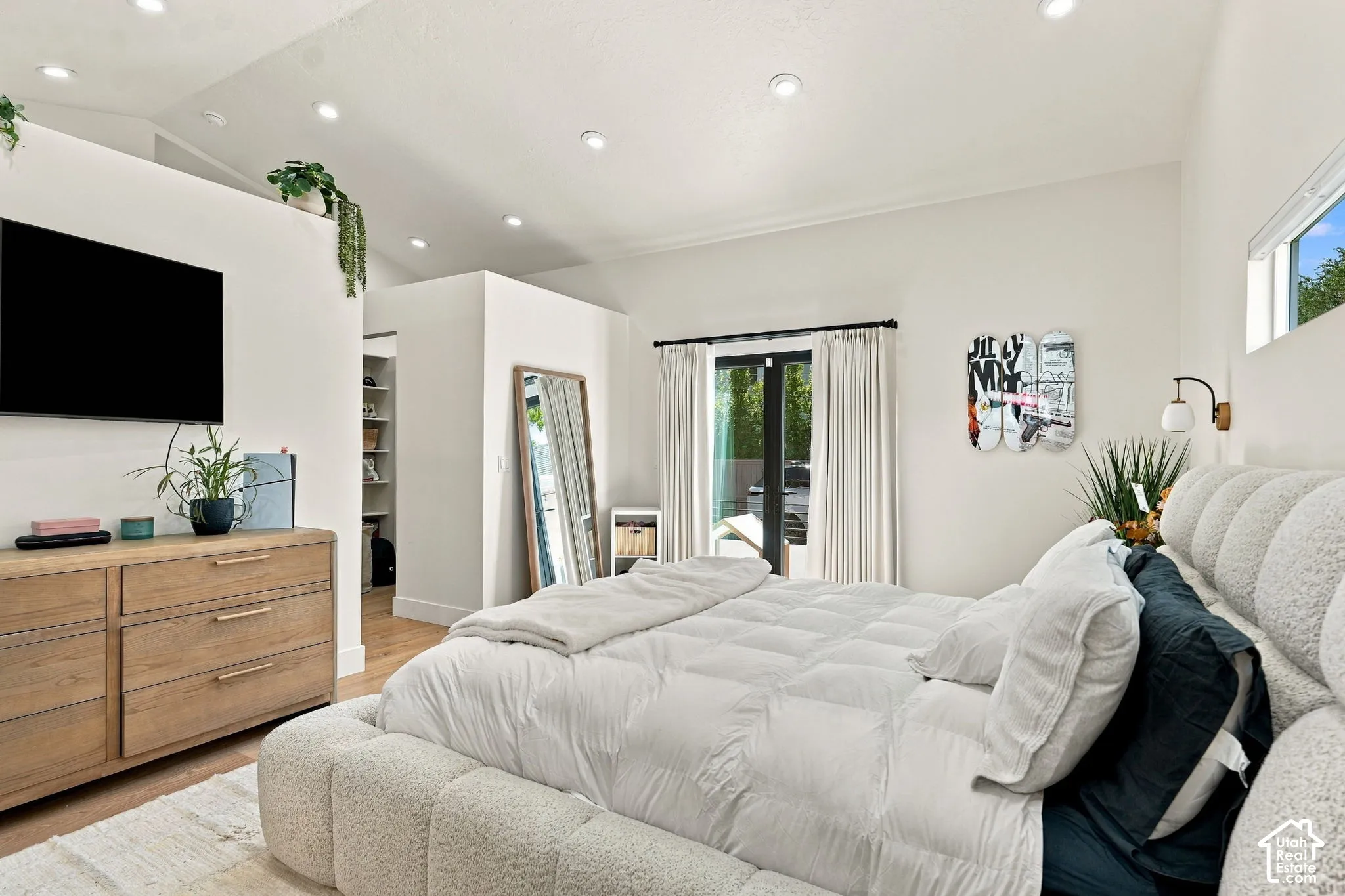 Vaulted ceiling with recessed lighting, wood-finish flooring, built-in shelving, glass-paned French doors, and a transom window