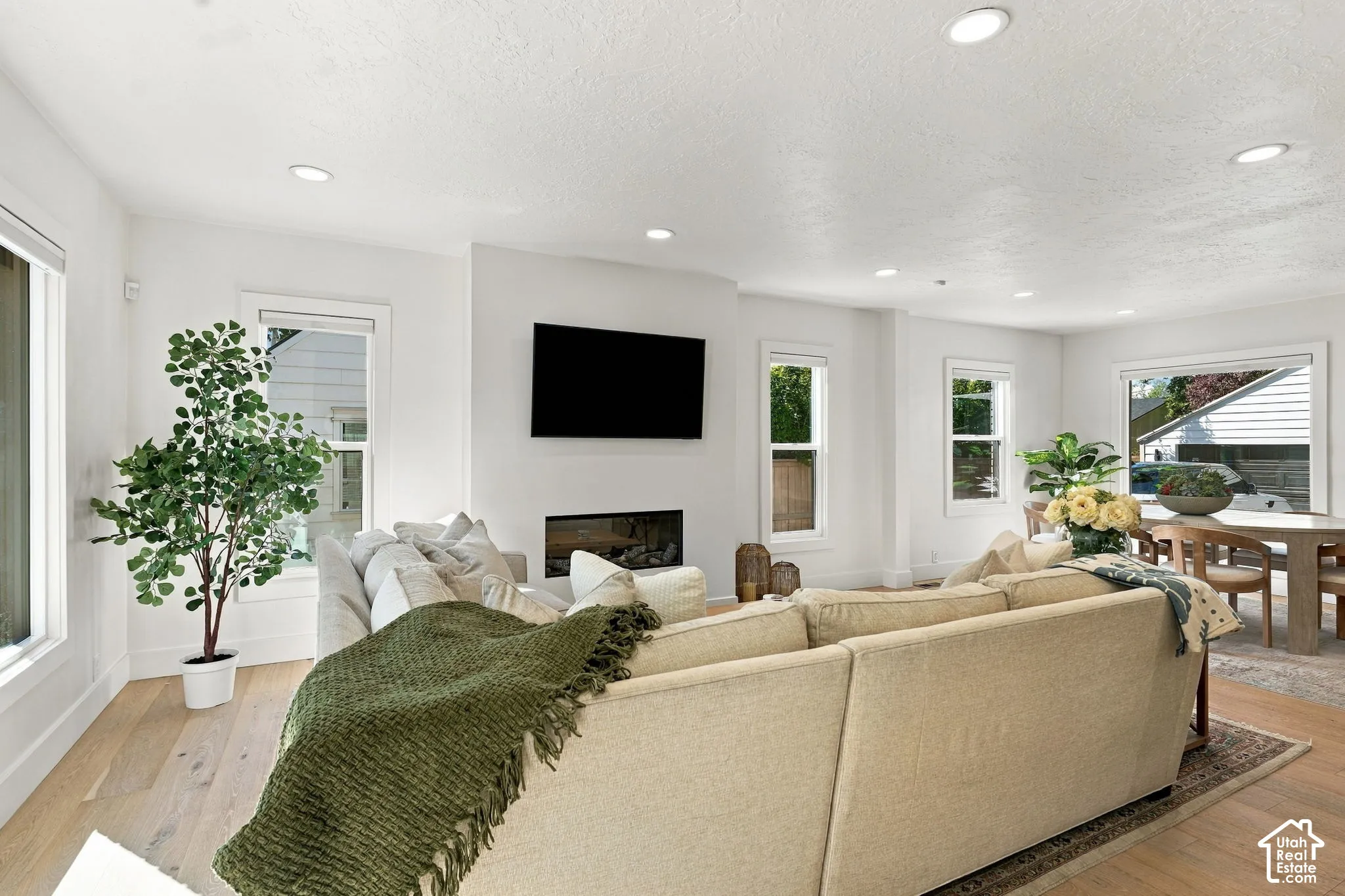 Recessed ceiling lighting, light wood-finish flooring, multiple windows, built-in fireplace, and a dining area