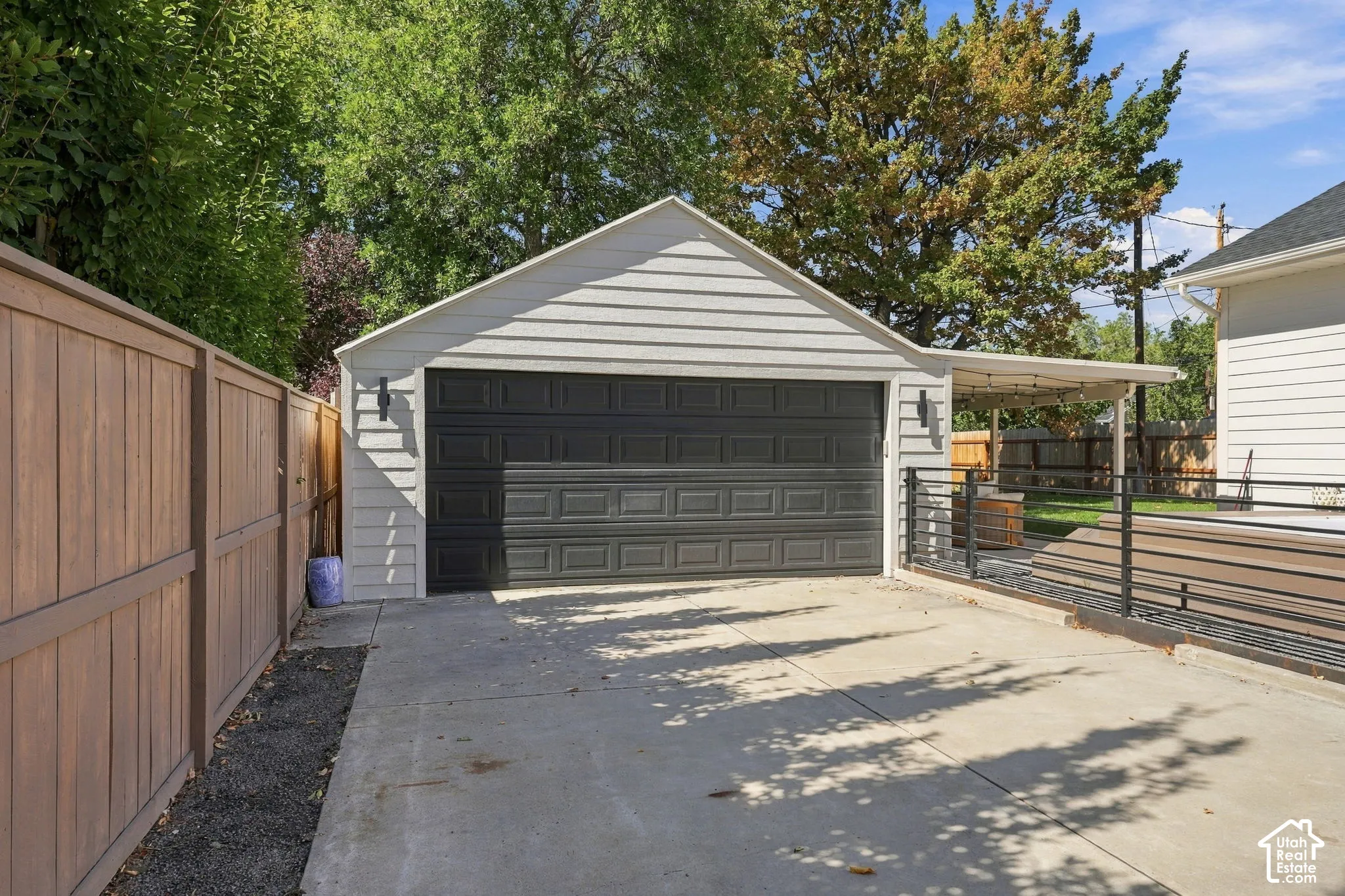 Detached garage with horizontal siding, a dark paneled garage door, and a concrete driveway