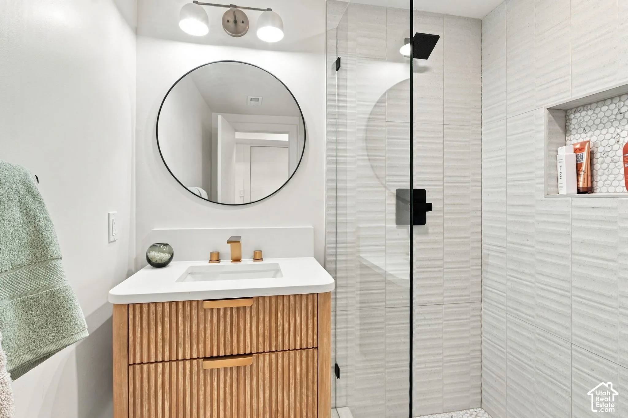 Glass-enclosed shower with textured wall tile and a recessed niche