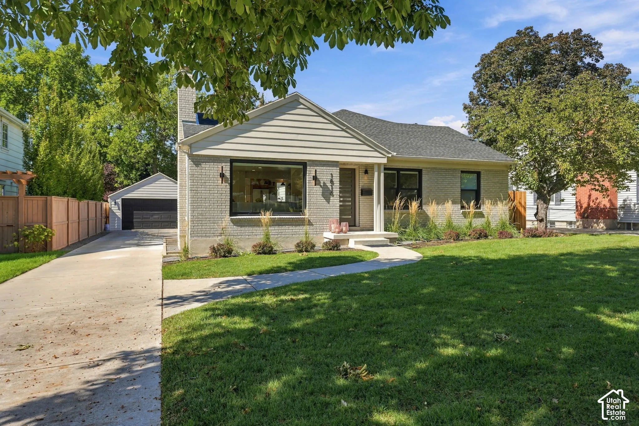 Light brick exterior with contrasting dark trim windows, gabled roofline, and established landscaping