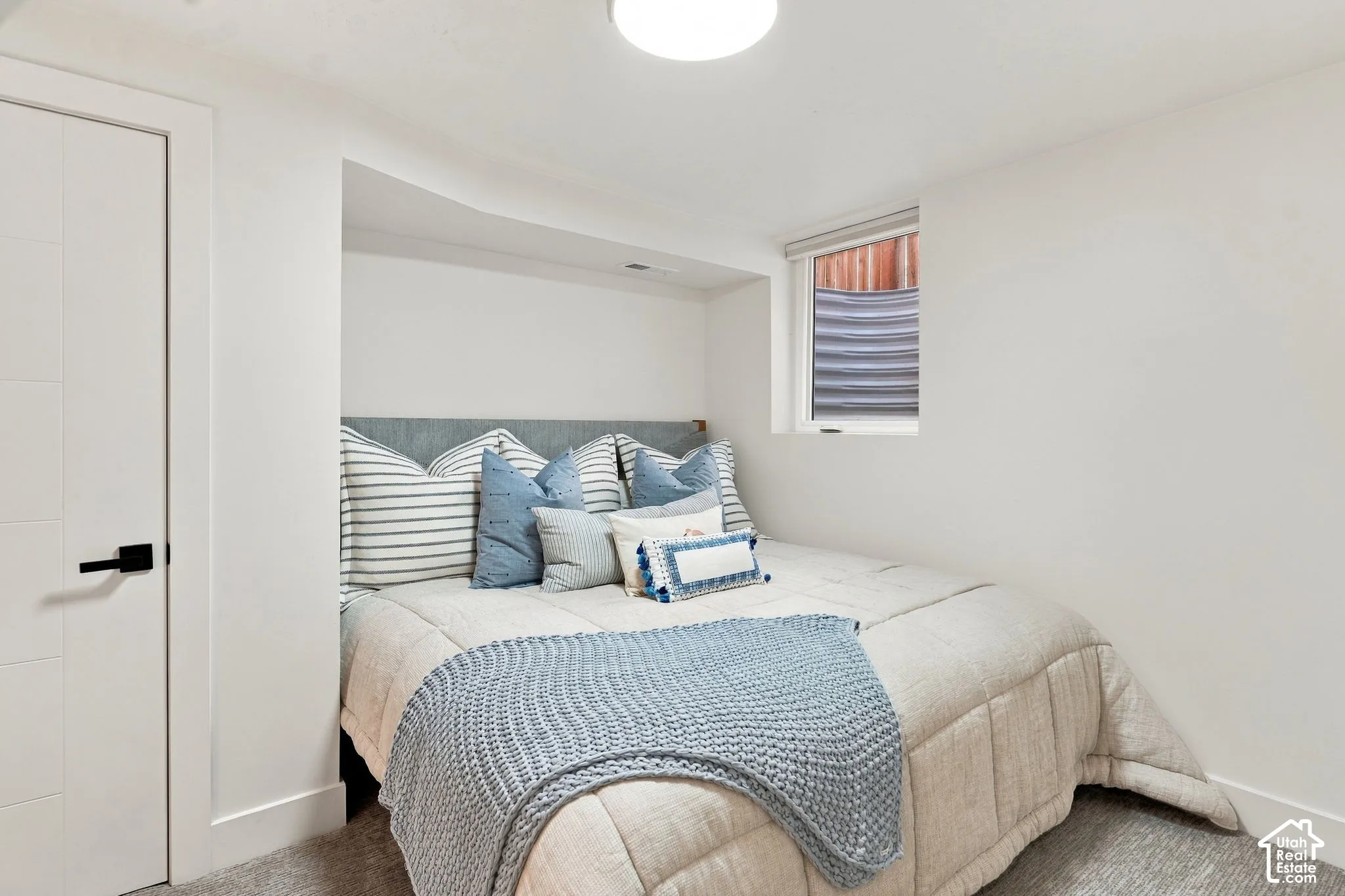 Recessed sleeping area with a window, white walls, and a contemporary door with a matte black handle