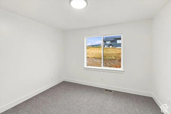 Recessed lighting, white walls, gray carpet flooring, and a large window