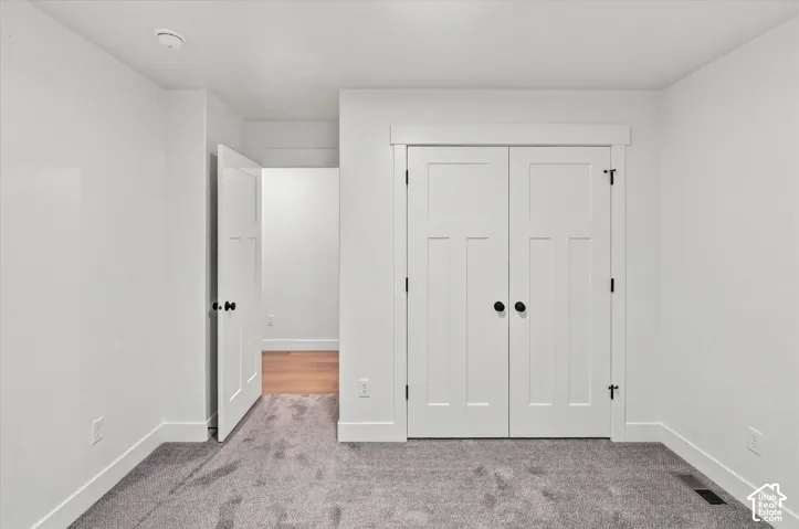 Plush gray carpeting, white walls, white trim, and a white bi-fold closet door