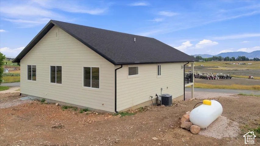 Contemporary exterior with horizontal siding, dark shingle roof, white window frames, and a visible HVAC unit
