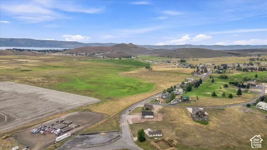 Expansive landscape featuring open fields, distant mountains, and a body of water