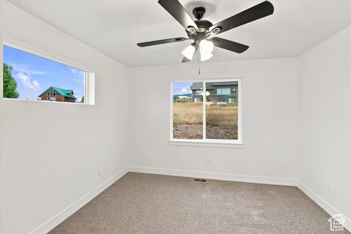 Recessed window, large picture window, ceiling fan with integrated lighting, and carpet flooring