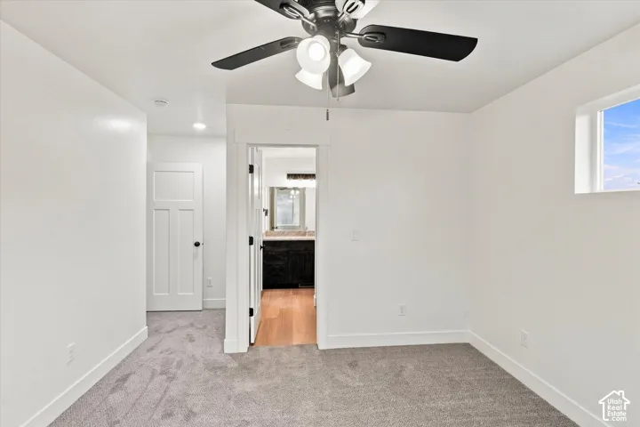 Plush grey carpeting with clean white walls and trim, featuring a ceiling fan with integrated lighting