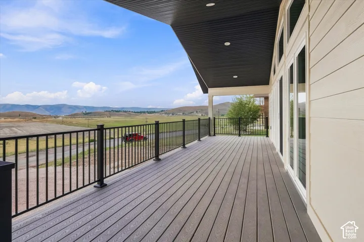 Spacious outdoor deck with composite decking and black metal railings, complemented by an overhead soffit and light-toned siding