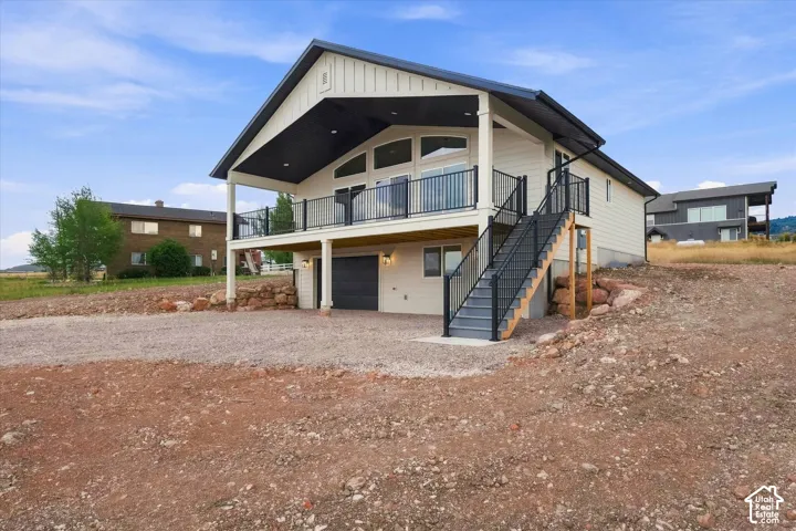 Contemporary residence featuring a covered balcony with metal railing, a two-car garage, and an exterior stairway