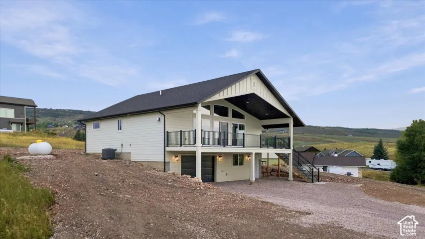 Contemporary exterior with white siding and dark trim, featuring a covered elevated balcony with black railings and a ground-level patio