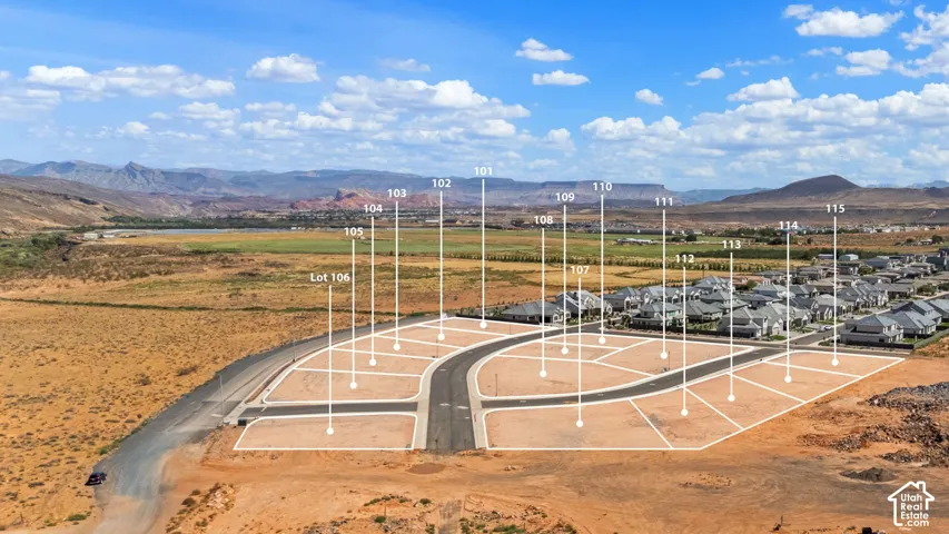 Expansive aerial of a residential development featuring graded lots with paved roads, surrounding desert landscape, and distant mountains