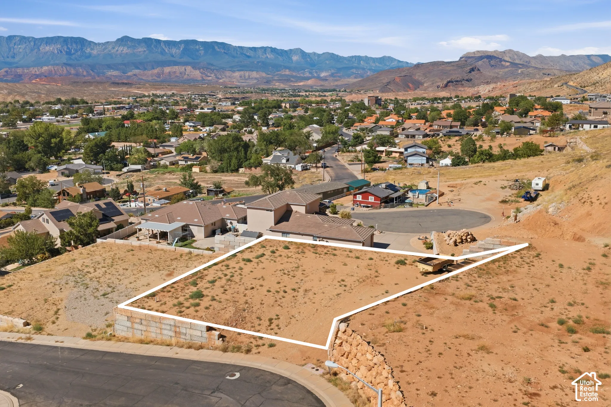 Expansive undeveloped lot with a visible property boundary, situated on a sloped terrain