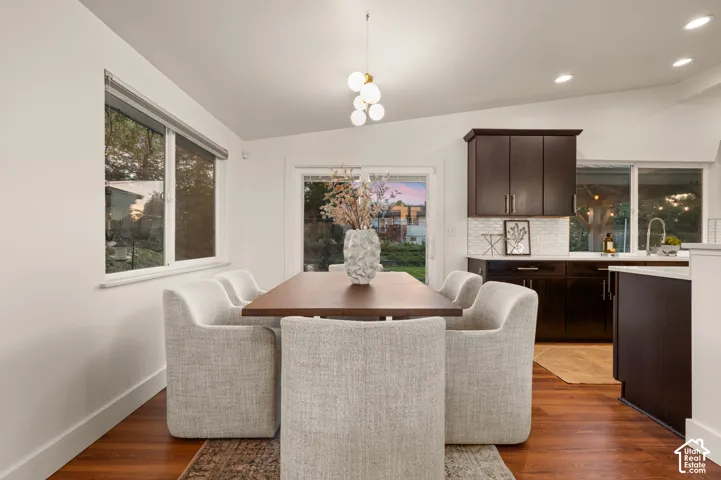 Vaulted ceilings with recessed lighting, wood-finish flooring, white shaker cabinetry, white tiled backsplash, and stainless steel sink with gooseneck faucet