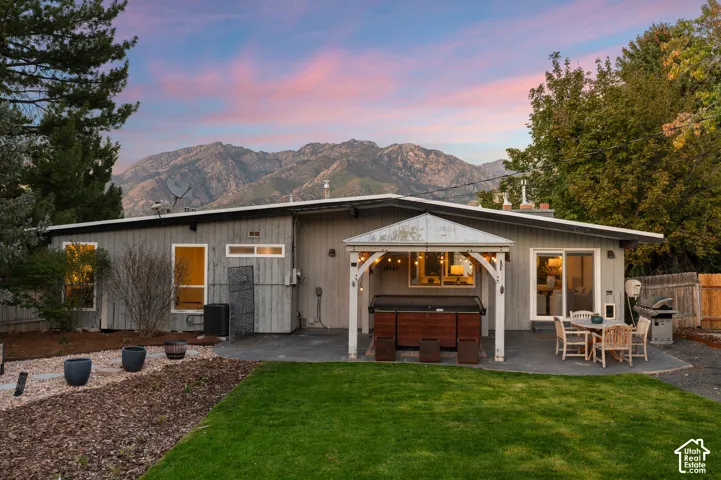 Expansive backyard featuring a lush lawn, a patio, and a covered hot tub area