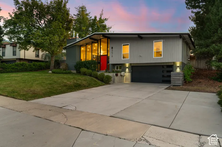 Modern exterior with expansive windows, a vibrant red entry door, a two-car garage, and a concrete driveway