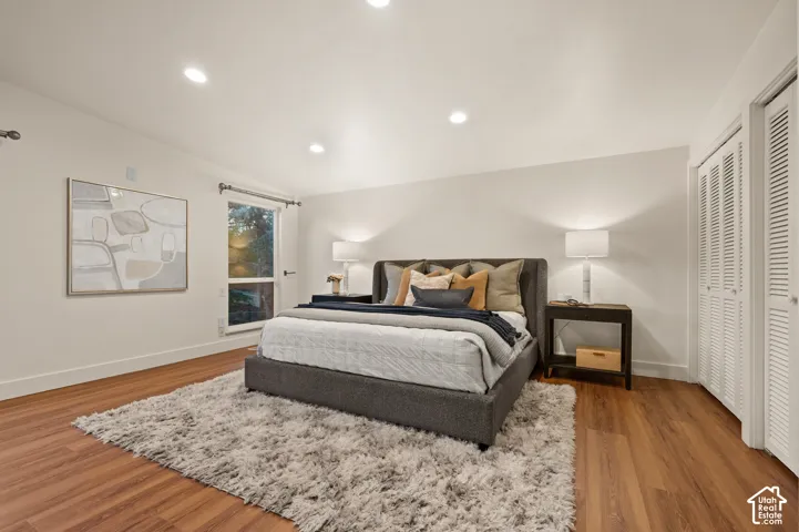 Recessed ceiling lighting, wood-finish flooring, white walls, and louvered closet doors