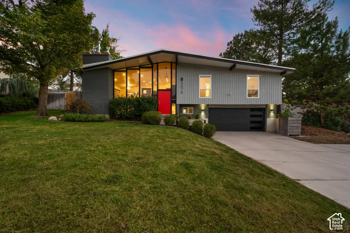 Modern architectural style featuring an angled roofline, extensive front-facing windows, and a vibrant red entry door