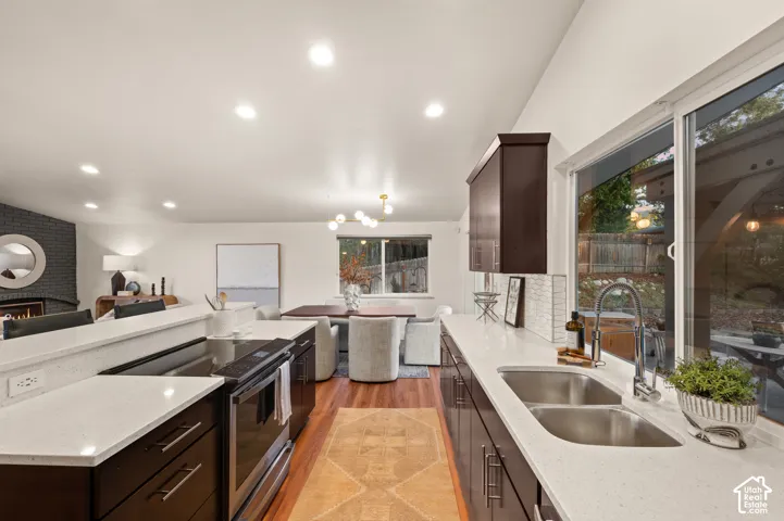 Chef's kitchen featuring dark wood cabinetry, stainless steel appliances, white quartz countertops, dual undermount sinks, and recessed lighting throughout