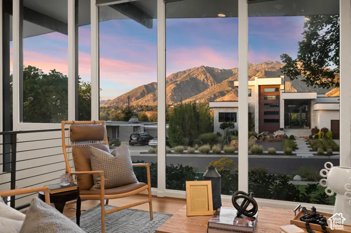 Floor-to-ceiling windows, wood-finish flooring, and a mountain backdrop