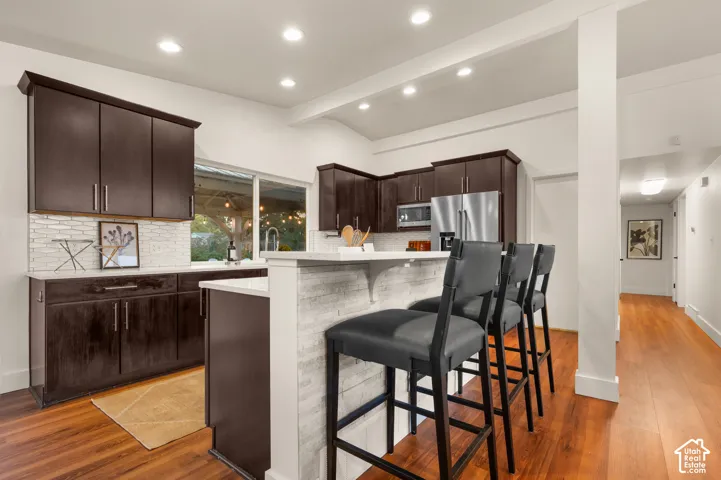 Kitchen featuring dark wood-finish cabinetry, white countertops, tile backsplash, and stainless steel appliances