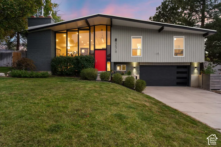 Modern architectural exterior with a distinctive sloping roofline, expansive floor-to-ceiling windows, and a vibrant red entry door